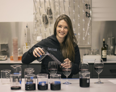 a woman pours wine in a winemaking lab