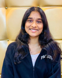 Young Desi woman sits on golden furniture and smiles at camera