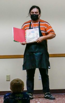 A librarian holds a book reading to students.