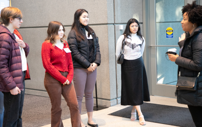 Young women stand and listen to a woman talk