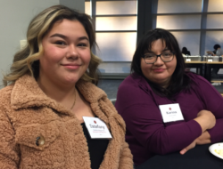 Two women smiling and sitting next to each other.