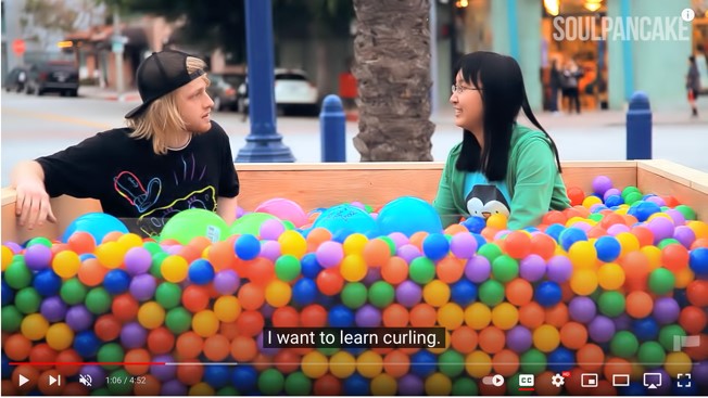 a man and a woman sit in a ball pit, having a conversation