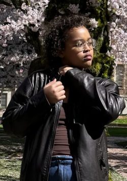 girl leans against a blooming cherry tree and looks to the right