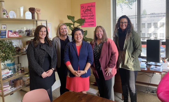 four women stand in a row, smiling at the camera. Left to right: Policy Director Jayme Shoun, Chief Impact & Policy Officer, Jenée Myers Twitchell, Senator Emily Randall (26th LD), Kareen Borders, and Lisa Heaman.