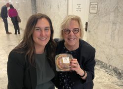 Jayme Shoun and Senator Claire Wilson crouch, Senator Wilson holds a mini pie.