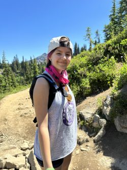 student on a hiking trail turns and smiles at the camera