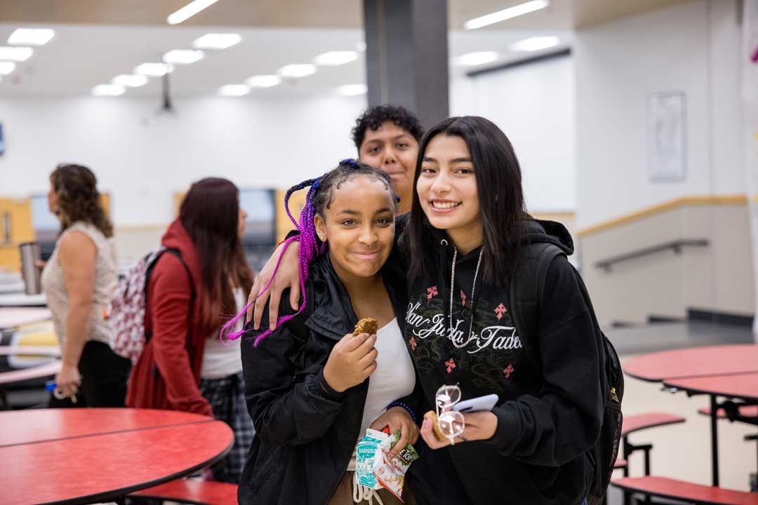 اثنان من طلاب المدرسة الثانوية يبتسمان للكاميرا أثناء وقت الغداء.