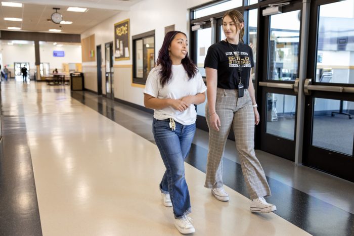 a school counselor and student walking down a long hallways in Royal High School