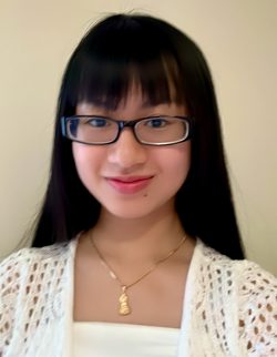 Girl in white top and gold necklace smiles at the camera