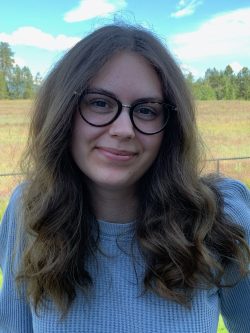 young woman with blonde hair and glasses smiles at camera